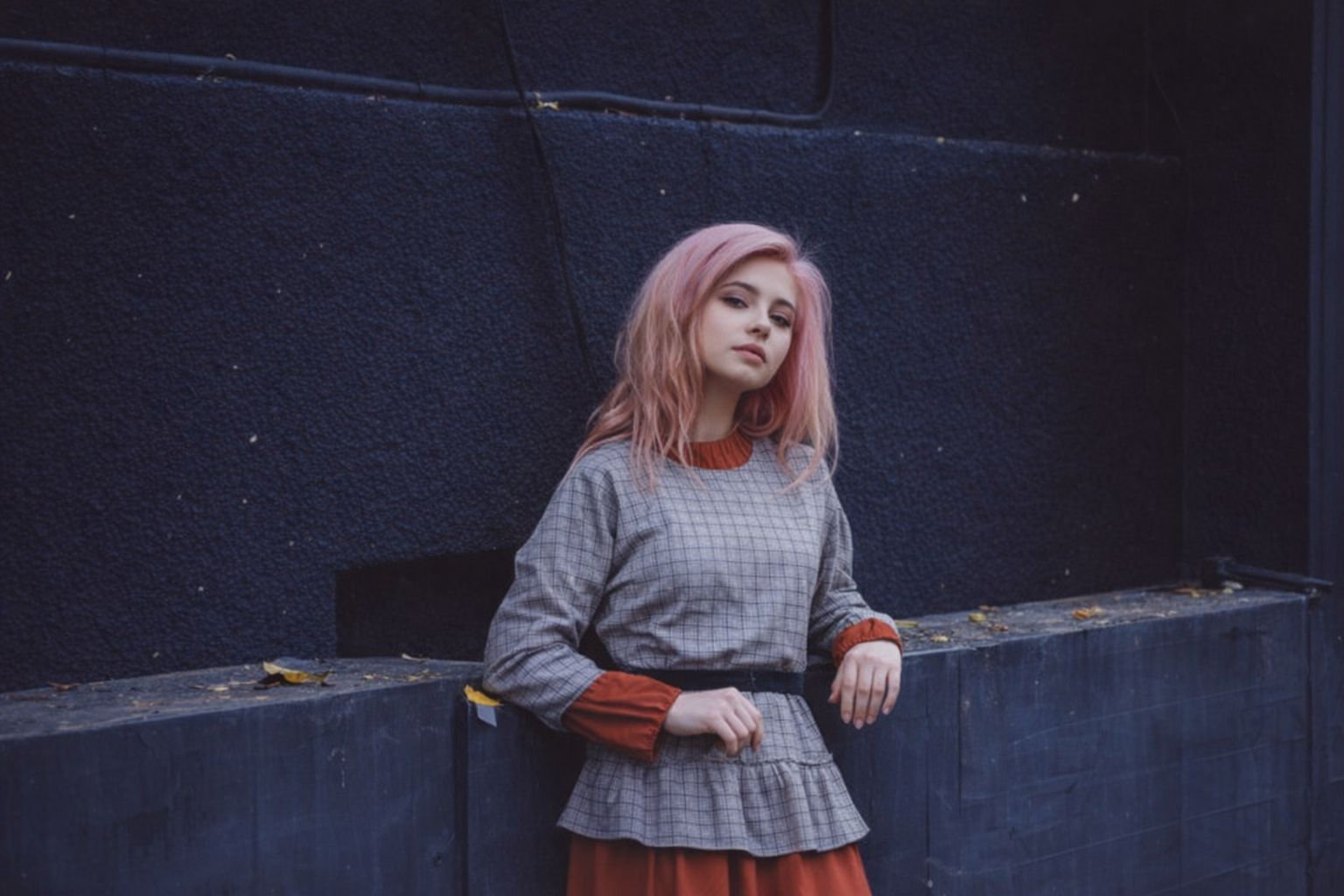 Młoda dziewczyna w różowych włosach prezentuje jesienną stylizację w kratę.